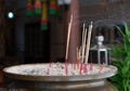 Incense sticks burning in a metal pot at a religious Thai Buddhist temple