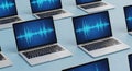 Multiple laptops displaying a blue digital waveform on their screens Royalty Free Stock Photo