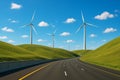 Multiple large wind turbines stand high above an empty highway, overlooking rolling green hills. Royalty Free Stock Photo