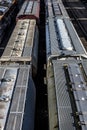 Multiple lines of covered hopper railroad train cars on tracks in trainyard