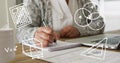 Multiple math concept icons against mid section of woman taking notes and using laptop Royalty Free Stock Photo