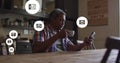Multiple message icons floating against senior using smartphone at home Royalty Free Stock Photo