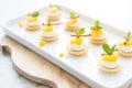 multiple mini lemon meringue tarts arranged on a platter