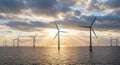 Offshore Wind Turbines in Sunset with Cloudy Sky and Calm Water Royalty Free Stock Photo