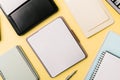 Multiple open notebooks and devices on desk with blank pages, pens, and stationery items arranged on yellow surface with copy Royalty Free Stock Photo