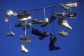 Multiple pairs of shoes flung over electric wire by shoelaces