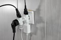 Multiple plugs in wall electrical outlet is dangerous overload, close-up