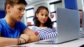 Multiple red heart icons over caucasian boy and girl using laptop at school