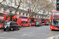 Multiple red London double decker buses in front of Waldorf Hotel with taxis