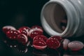 Multiple red and white pills spilled from bottle on black background Royalty Free Stock Photo