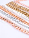 Multiple rows of linked chains in rose gold, white, silver, and gold laid on a bright white surface Royalty Free Stock Photo