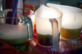 Multiple semi transparent plastic and transparent glass jars placed on a table for making soap icing, cake