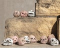 Multiple small fired clay head sculptures with different facial expressions on a stone display in Marfa, Texas.