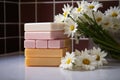 multiple soap bars stacked with fresh daisies in between on a tiled countertop