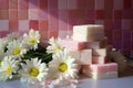 multiple soap bars stacked with fresh daisies in between on a tiled countertop