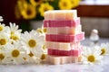 multiple soap bars stacked with fresh daisies in between on a tiled countertop