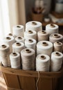Multiple spools of thread in beige, white, and ivory tones are arranged in a wooden basket. Each Royalty Free Stock Photo