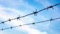Multiple strands of barbed wire fence stretching across a bright blue sky clouds Royalty Free Stock Photo