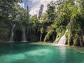 Multiple waterfalls pouring into turquoise lake in forest Royalty Free Stock Photo