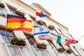 Multiple waving flags on a building facade in the wind, Israel, Germany, Spain, USA, Poland, European Union, Italy, France, UK