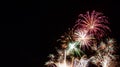 Multiple white starburst fireworks with red, green, and gold highlights with a black background