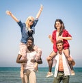 Multiracial best friends at beach having fun with piggyback game Royalty Free Stock Photo