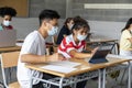 Multiracial boy and girl teen students with face mask using tablet in class. Group of teenagers studying in high school Royalty Free Stock Photo