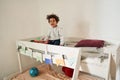 Multiracial boy laughing and looking at the camera while sitting at the second tier of his bed