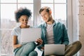 Multiracial boyfriend and girlfriend using laptops while sitting