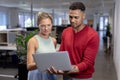 Multiracial business advisors discussing over laptop while standing at modern workplace