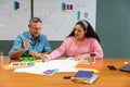 Multiracial businessman and businesswoman discussing strategy over documents in creative office Royalty Free Stock Photo