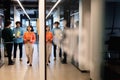 Multiracial colleagues discussing while businesswoman walking with tablet pc in corridor at office Royalty Free Stock Photo