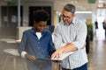 Multiracial colleagues discussing over document file while standing together at modern workplace Royalty Free Stock Photo