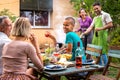 Multiracial couple cooking food on grill for friends. Outdoor garden barbecue party. Friends laughing and having fun. Royalty Free Stock Photo