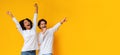 Multiracial couple dancing and singing together, having fun over yellow background