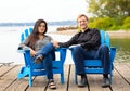 Multiracial couple in late forties on blue chairs by lake