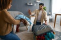 Multiracial couple packing clothes into travel suitcase