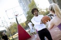 Multiracial couple playing basketball on outdoor court at outumn day