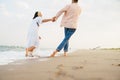 Multiracial couple smiling and holding hands while walking on beach Royalty Free Stock Photo