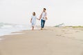 Multiracial couple smiling and holding hands while walking on beach Royalty Free Stock Photo