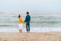 Multiracial couple smiling and holding hands while walking on beach Royalty Free Stock Photo