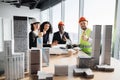 Multiracial coworkers builders and architects sitting at table with blueprints Royalty Free Stock Photo