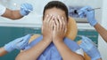 Multiracial doctors in rubber gloves scare girl with medical instruments