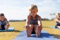 Multiracial elementary schoolboys touching toes while exercising on yoga mat in school ground