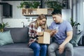 Multiracial family at home on the couch disappointed to receive a parcel, cheated in an online store, a man and a woman sitting on Royalty Free Stock Photo