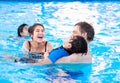 Multiracial family swimming together in pool. Disabled youngest Royalty Free Stock Photo