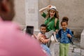 Multiracial family travelling together with small kids. Taking photo in old city cetre.