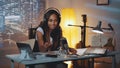 Multiracial female journalist doing online interview on the computer in home recording studio