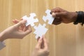 Multiracial female male hands holding puzzle pieces above table