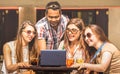 Multiracial friends at cocktail bar having fun with laptop - Connected community of young students people using pc on social media Royalty Free Stock Photo